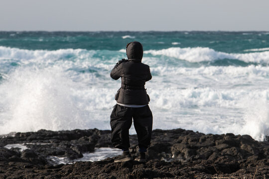 a female tourist on rocky seaside against windy sea