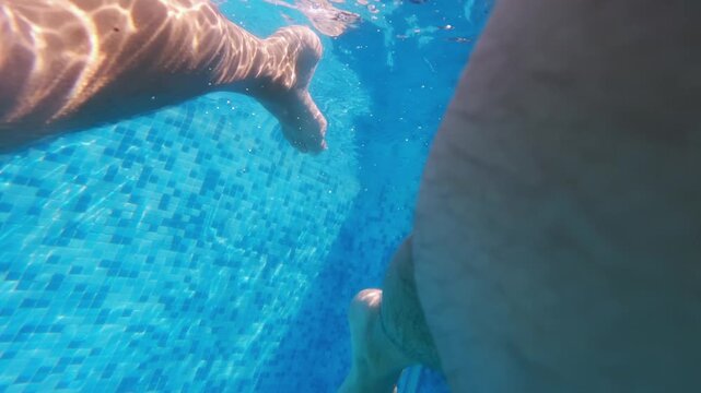 Underwater view of legs swimming freestyle crawl in a clear blue pool