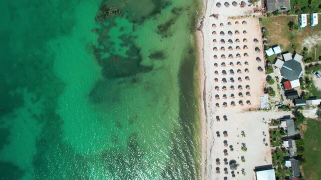 Aerial view of a summer beach in Orikum, Albania, with umbrellas and turquoise water