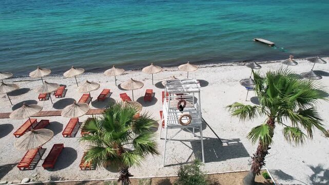 Tranquil beach with safeguard platform in Orikum, Albania with precisely arranged parasols and sun loungers