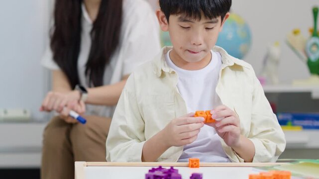 Young Asian Boy Using Mathematics Linking Cubes in Classroom Setting