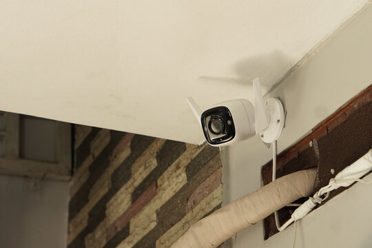 Modern White Wireless Outdoor Security Camera Mounted on Exterior Wall for Surveillance and Home Protection