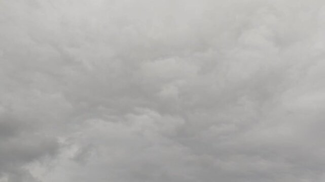 Deep blue sky holds heavy dark clouds. Large rainy shapes move across a wide view. Thick white layers mix with gray storm banks. Thunder may come soon. Wind pushes big formations slowly.