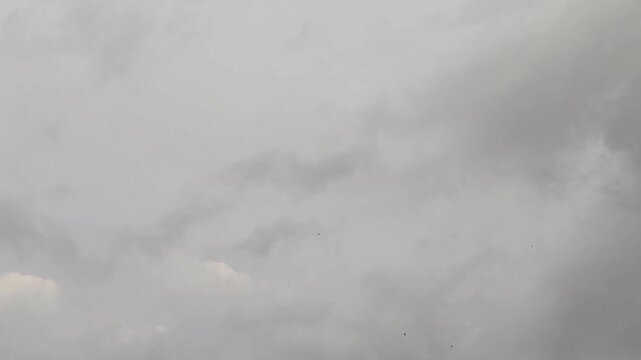 Deep blue sky holds heavy dark clouds. Large rainy shapes move across a wide view. Thick white layers mix with gray storm banks. Thunder may come soon. Wind pushes big formations slowly.