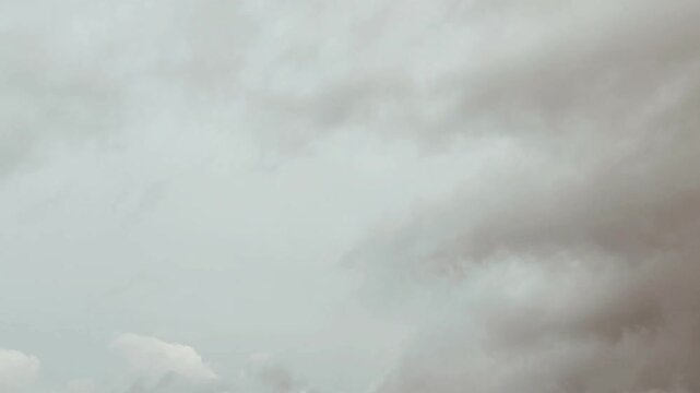 Deep blue sky holds heavy dark clouds. Large rainy shapes move across a wide view. Thick white layers mix with gray storm banks. Thunder may come soon. Wind pushes big formations slowly.