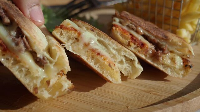 Hand Picking Up a Delicious Panini Sandwich with Melted Cheese