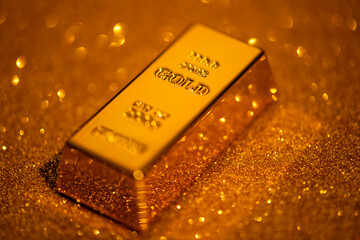 Gold precious metal in golden background. Gold bullion on premium metallic surface. Gold asset for...