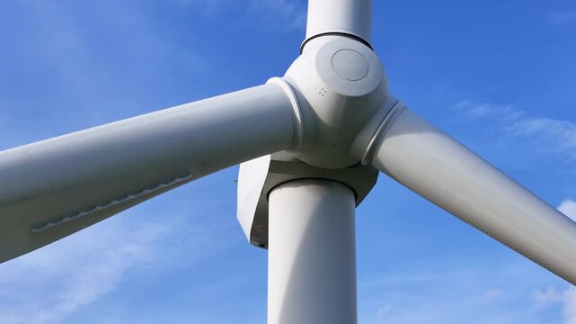 crisp low wind turbine hub three blades against clear blue sky scale environmental value clean energy technology generating reveals up close smooth angle 