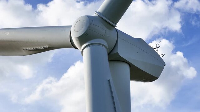 perspective wind turbine rounded hub three blades framed by soft blue sky light clouds clean efficiency renewable energy producing sustainable upward electricity 