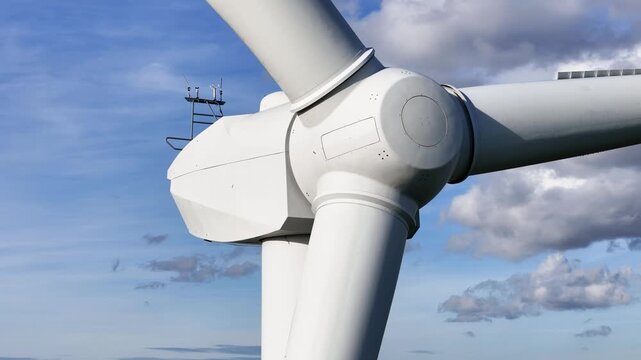 wind turbine nacelle central hub two blades against vivid blue sky scattered clouds advanced engineering sustainable powered up close side view electricity renewable power 