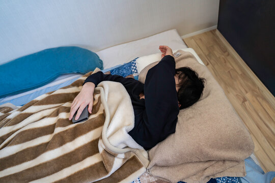 布団で寝る落ち込む男性