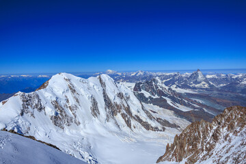 Mountain glacier panorama with summits Lyskamm, Breithorn, Mont Blanc massif (background middle) and Matterhorn (background right) seen from Zumsteinspitze in Pennine Alps, Switzerland