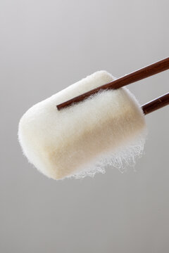 Close-up of chopsticks picking up a piece of hairy tofu