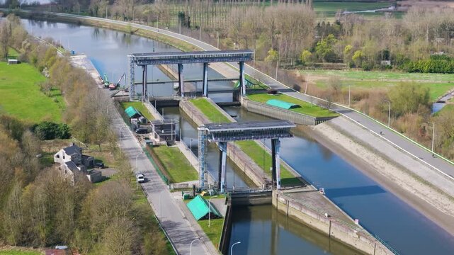 high oblique dual lift gate lock steel towers glass corridors calm water curved river channel excavator quiet roads through trees farmland rural aerial shot lift-gate 