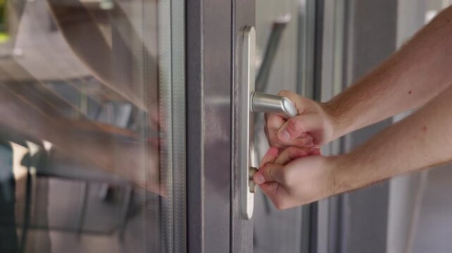 Man unsuccessfully trying to open locked door with broken lock, turning key and pulling handle without success