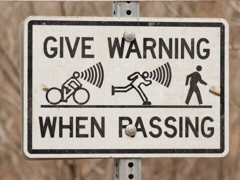 Sign on a walking / hiking trail that says to give warning when passing