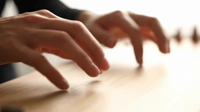 Close-up of hands delicately interacting with a wooden surface.