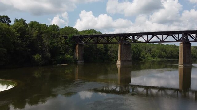 Drone crossing the Grand River, the largest river entirely within Ontario, Canada, as it passes through the town of Paris. Railroad train bridge and Penman's Dam.
