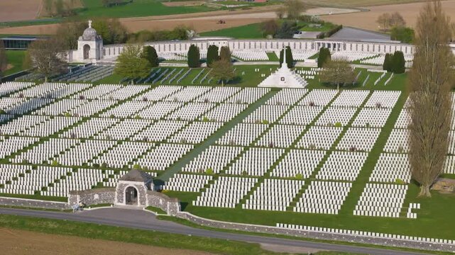 dense regimented white headstones converge cross sacrifice arched entrance pavilion curved memorial wall belgian countryside stretch quietly beyond cemetery toward tyne cot wwi 