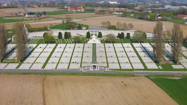 tyne cot cemetery semi circular memorial wall stone staircase frame thousands uniform white headstones precise rectangular plots vivid green lawns tall poplars patchwork farmland wwi 