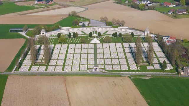 tyne cot cemetery crisp rectangular layout white headstones intersects dark green pathways cross sacrifice rises center memorial wall domed pavilions tall poplars wwi zonnebeke belgium 