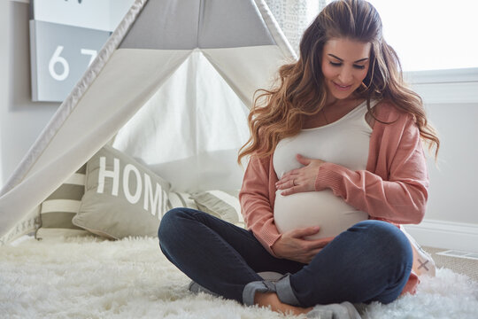 Happy, relax and pregnant woman in home by tent with maternal bonding, love and connection. Smile, pregnancy and female person holding belly with maternity or prenatal care in nursery room at house.