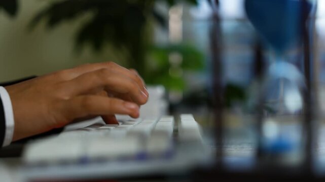 Hand typing on white keyboard, Close-up of a person's hand typing on a white computer keyboard in a softly lit indoor setting