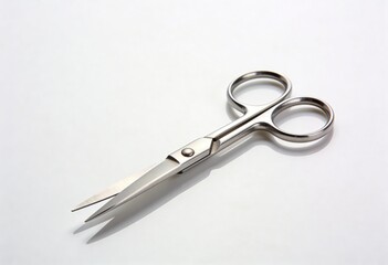 Obraz premium Small pair of silver metallic scissors lying open on a white surface