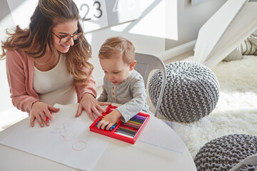 Mother, kid and smile in home with crayon, education and learning for early childhood development....