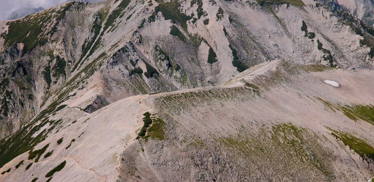 Rugged mountain ridge with hikers and snow patches