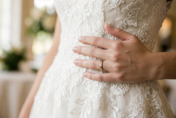 レースのウェディングドレスにそっと触れる結婚指輪の手―花嫁の特別な瞬間を切り取った上質ブライダル素材