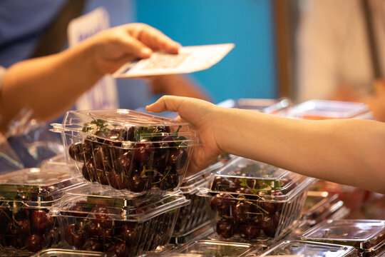 Woman choosing cherries in plastic box, woman shopping fruits in market, local vendor street commerce, close up, at Wang Lang Market.
