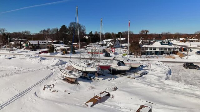 Aerial Drone View of Yachts at Gosport in Brighton Ontario with Frozen Snow Covered Landscape Under Blue Sunny Winter Sky
