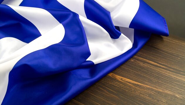 Close-up of a fabric with alternating blue and white stripes draped across a wooden surface with a dark background