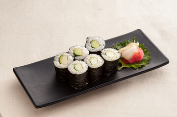 Cucumber Sushi Rolls (Kappa Maki) with Pickled Ginger and Wasabi on a Black Plate © n3moh3ro