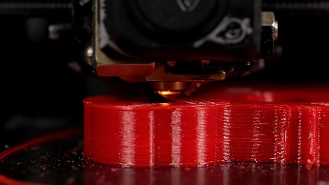 Macro detail of a 3D printer fabricating a red object, showcasing technology and industry with 3D printing precision manufacturing.