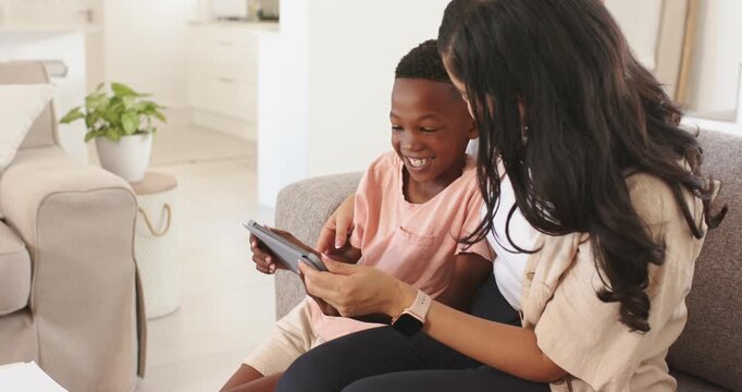 Mother presenting tablet, son tapping and laughing, mother guiding fingers, sharing tech education