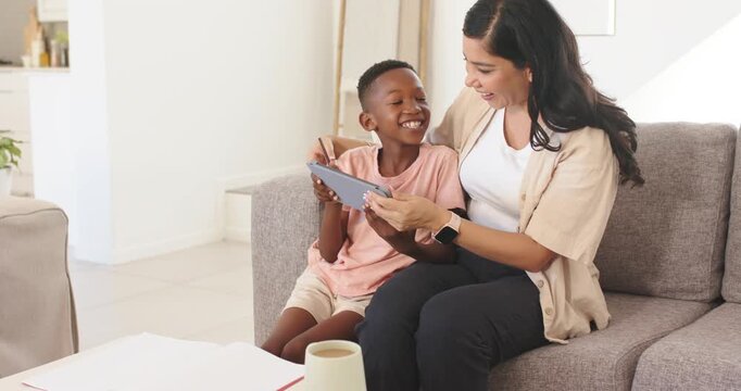 Diverse midadult woman and youth boy sitting sofa pointing, drawing on tablet with stylus, learning