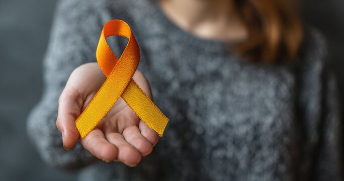 Person holding an orange awareness ribbon for Multiple Sclerosis awareness.