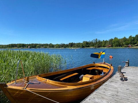 Old wooden boat docked on lake in the summer