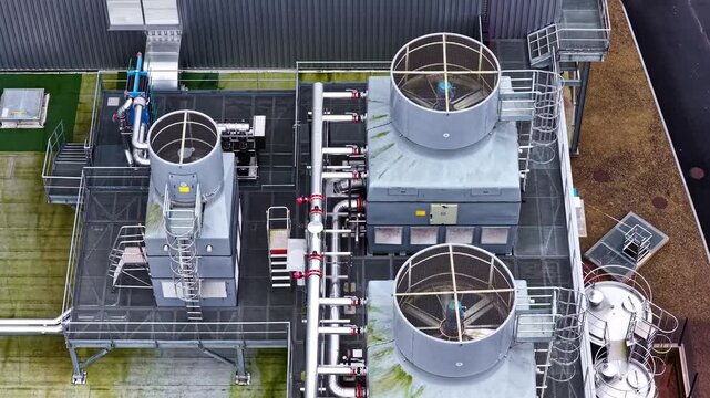 Aerial top view over dairy processing facility rooftop showing cooling towers pipes and industrial refrigeration equipment