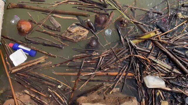 Heavy plastic garbage and organic waste floating on river surface, water pollution environmental disaster caused by household trash and debris clogging the natural aquatic ecosystem flow