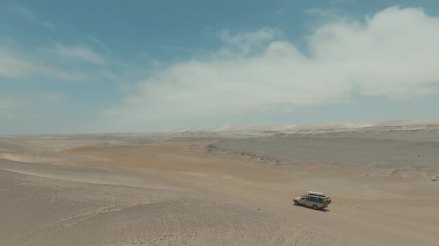 Aerial Drone Tracking Shot of Car Driving on Desert Road Through Vast Landscape in Namibia