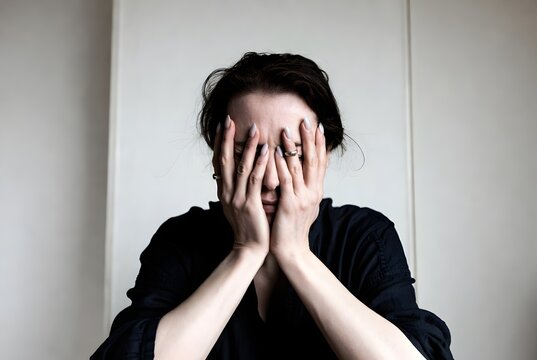 A woman clutches her face with her hands, a visual representation of anguish and the struggle with anxiety.