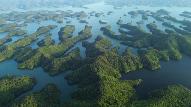 Drone flyover of Ta Dung Lake revealing green, symmetrical islands from above in Dak Nong, Central Highlands Vietnam. Majestic scenic aerial view of tropical lake landscape.