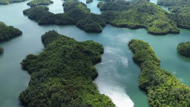 Drone close flyover over lush green islands on Ta Dung Lake in Dak Nong, Central Highlands Vietnam. Sunny day makes the tropical greenery vivid and scenic.