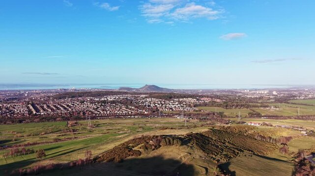 Aerial panorama of Edinburgh from Hillend: Cinematic drone flight over Midlothian farmland towards the city skyline and Firth of Forth