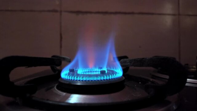 A gas stove burner with a blue and orange flame during the ongoing LPG crisis and rising cooking gas concerns