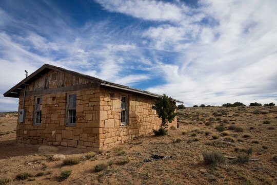 Old stone building in desert landscape under sweeping cloud formations