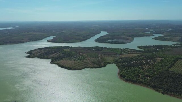 Aerial pan shot of patchwork farmland on a sunny day around Thac Mo Reservoir in Southern Vietnam.
